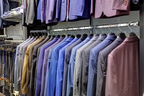 Row of men's suits hanging in closet.