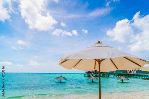 Beach chairs with umbrella at Maldives island, white sandy beach and sea . © jannoon028