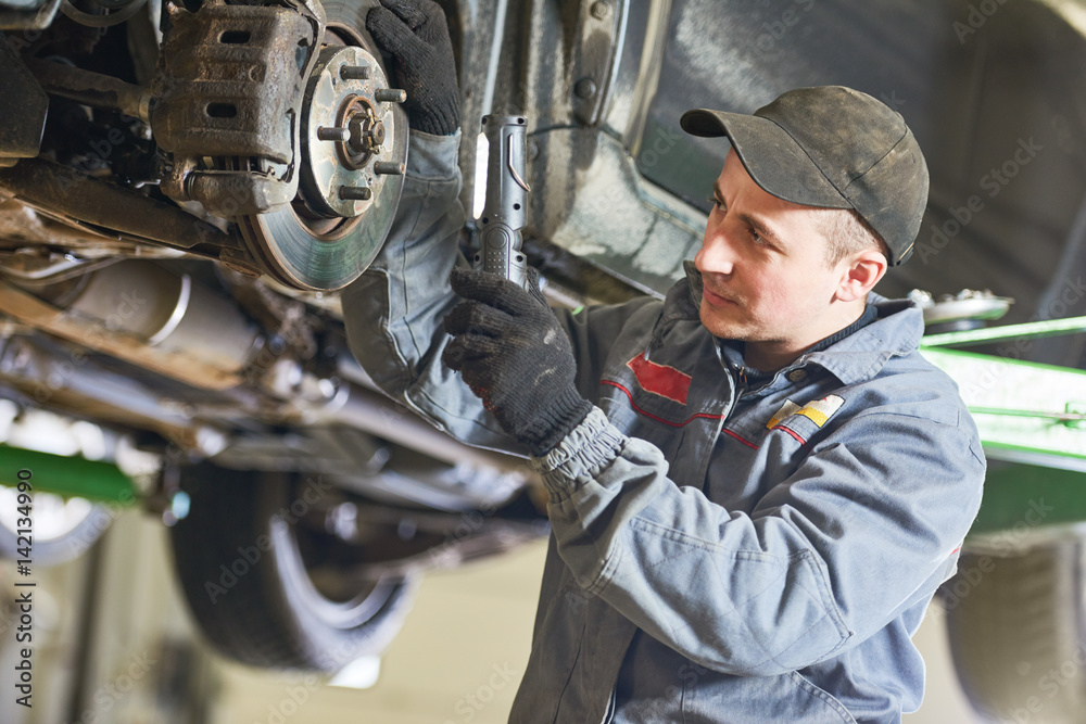 Auto repair service. Mechanic inspecting car suspension Auto repair service. Mechanic inspecting car suspension