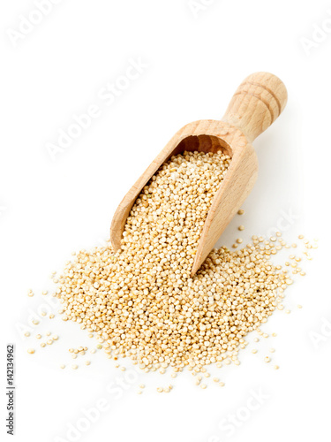 Raw, whole, unprocessed quinoa seed in wooden scoop on white