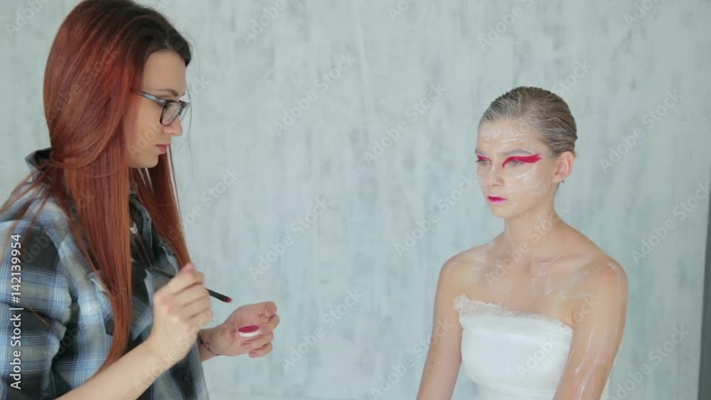 2 shots. Bodyart painting: professional make-up artist making body art in white room. Body paint, visage and fashion concept 2 shots. Bodyart painting: professional make-up artist making body art in white room. Body paint, visage and fashion concept