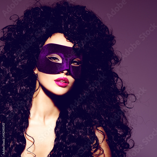 Beautiful woman with black hairs and violet theatre mask on face.