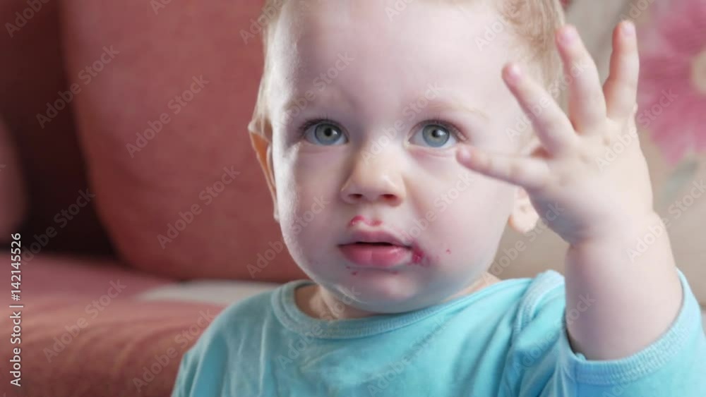 An attractive boy 2 years old eats a red beet salad. The face is smeared with porridge. Sits on the table. An attractive boy 2 years old eats a red beet salad. The face is smeared with porridge. Sits on the table.