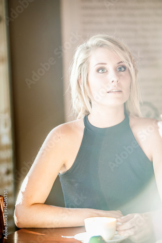 blonde female drinking coffee in a coffee shop