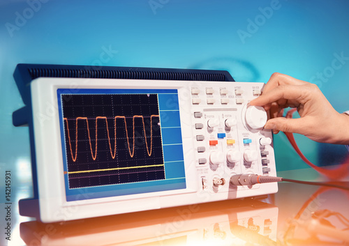 Modern electronic oscilloscope on abstract background photo