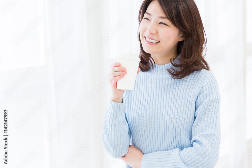部屋でコーヒーを飲む女性 紙カップ 部屋でコーヒーを飲む女性 紙カップ