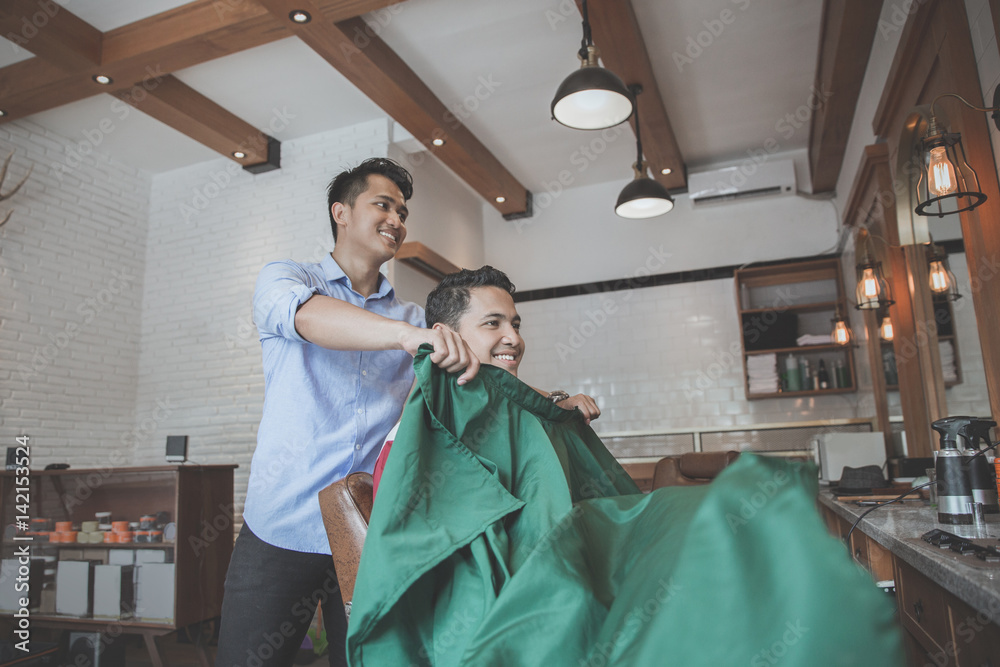 man put on barber's cape to his client man put on barber's cape to his client