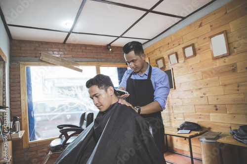 man getting haircut by hairdresser at barbershop