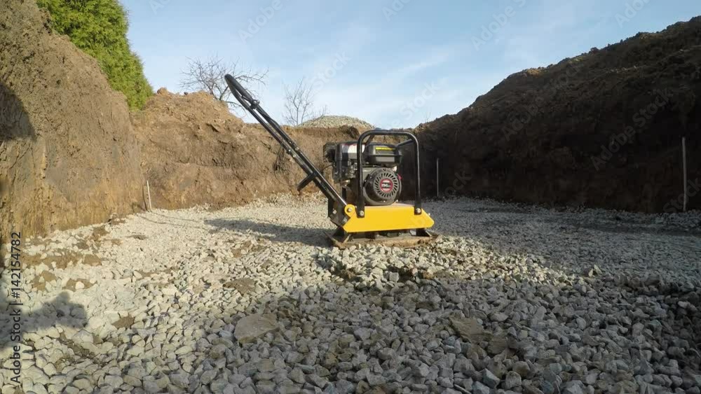 The man at the construction site. Man serving compacting machine. Stone