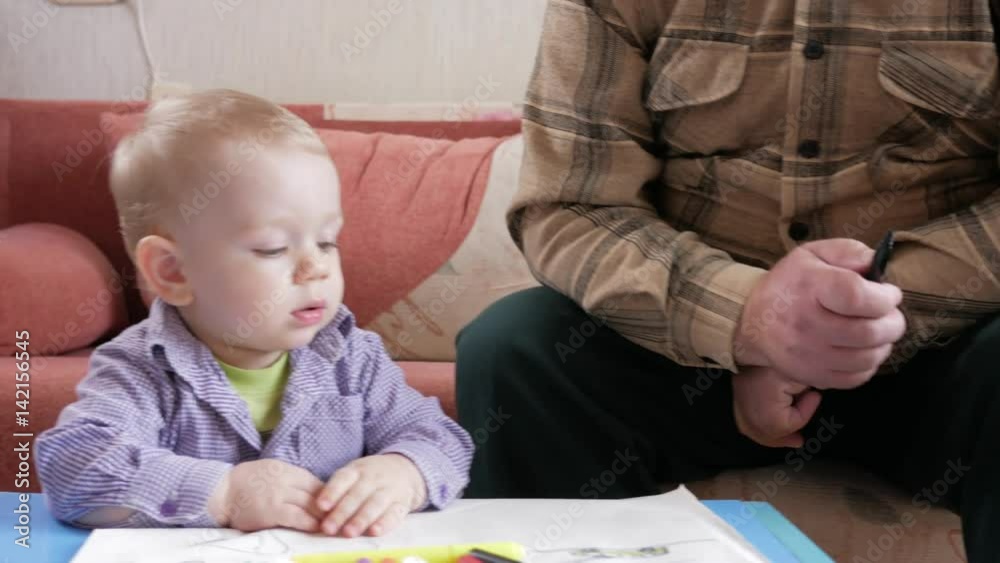 An attractive boy of 2 years and grandfather draw animals with a marker. Home decor. An attractive boy of 2 years and grandfather draw animals with a marker. Home decor.