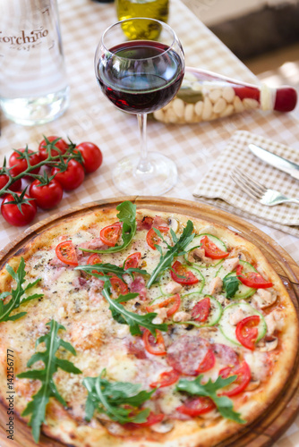 Pizza with glass of wine, on served table