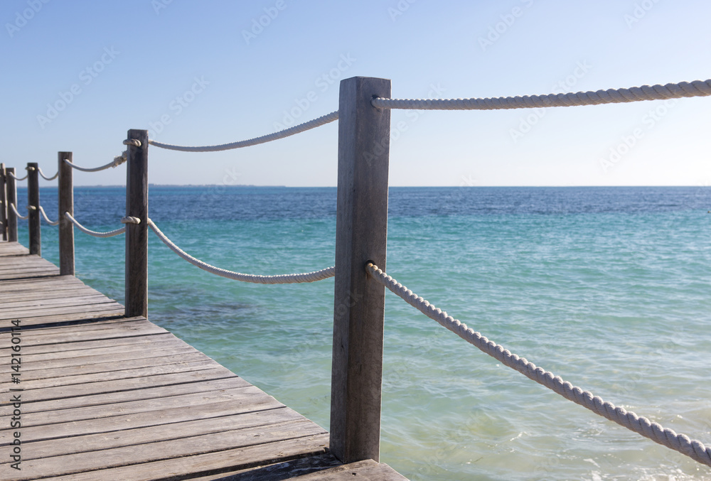 Obraz premium Beautiful scenery to the Caribbean sea. Wooden pier with rope fence. Turquoise water. Relaxing vacation time.