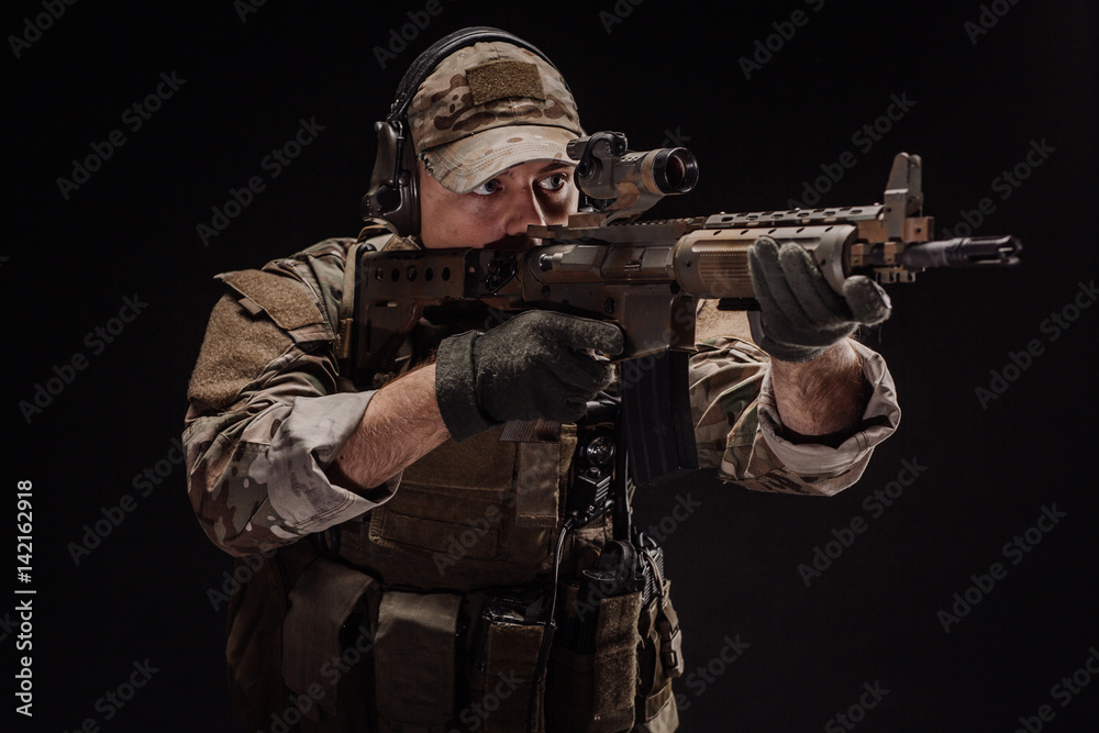 Portrait soldier or private military contractor holding sniper rifle. war, army, weapon, technology and people concept. Image on a black background.