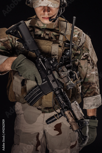 Portrait soldier or private military contractor holding sniper rifle. war, army, weapon, technology and people concept. Image on a black background.