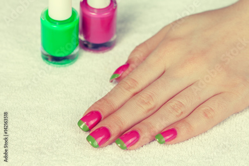 Beautiful female hand with bicolor green pink. Manicure salon