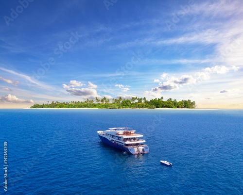 Big safari luxury yacht sailing on ocean, tropical island on background © Jag_cz