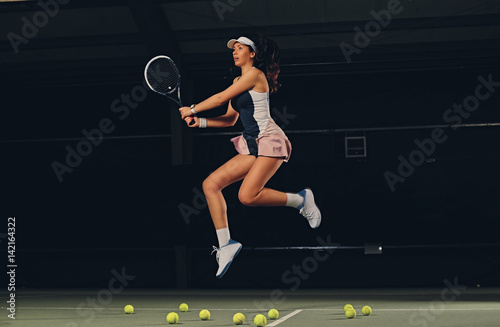 Female tennis player in a jump on a tennis court. © Fxquadro