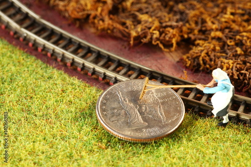 The money coin put on the miniature model railroad scenery represent the transportation business and model toy train concept related idea.