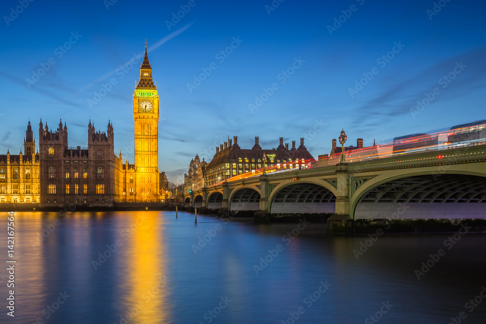 London, England - The Big Ben Clock Tower and Houses of Parliament with iconic red double-decker buses at city of westminster by night