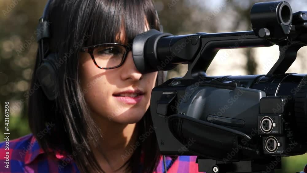 a pretty young brunette girl with a professional camcorder, outdoor a pretty young brunette girl with a professional camcorder, outdoor
