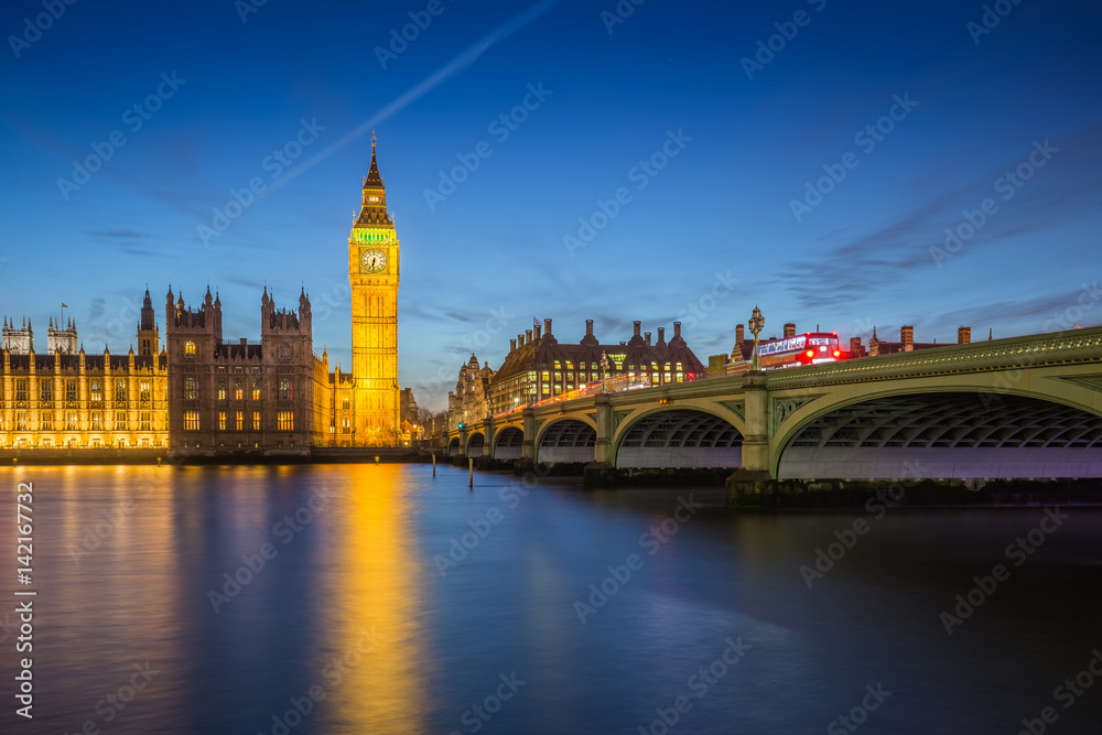 London, England - The Big Ben Clock Tower and Houses of Parliament with iconic red double-decker buses at city of westminster by night