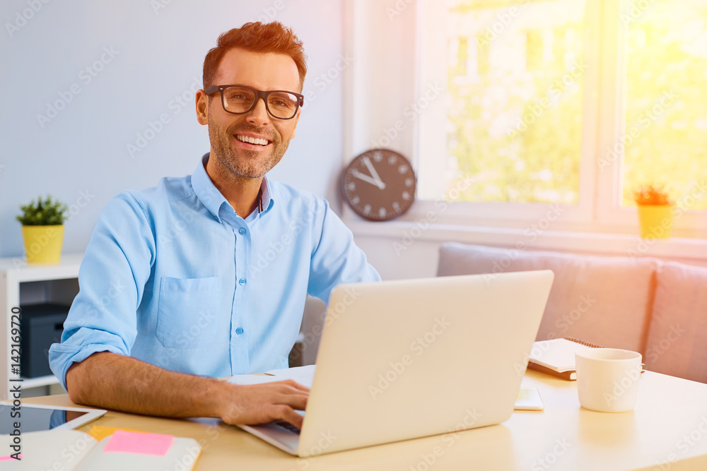 Portrait of happy man working on his laptop from home office Portrait of happy man working on his laptop from home office