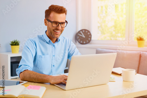 Happy man working with laptop from home photo