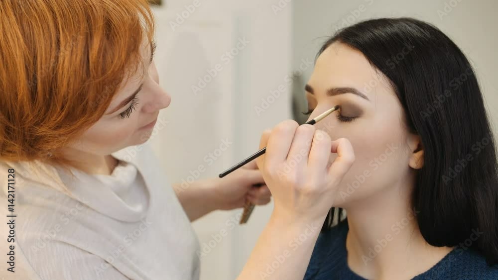 Close-up of a make-up artist applying make-up to the eyelash Close-up of a make-up artist applying make-up to the eyelash