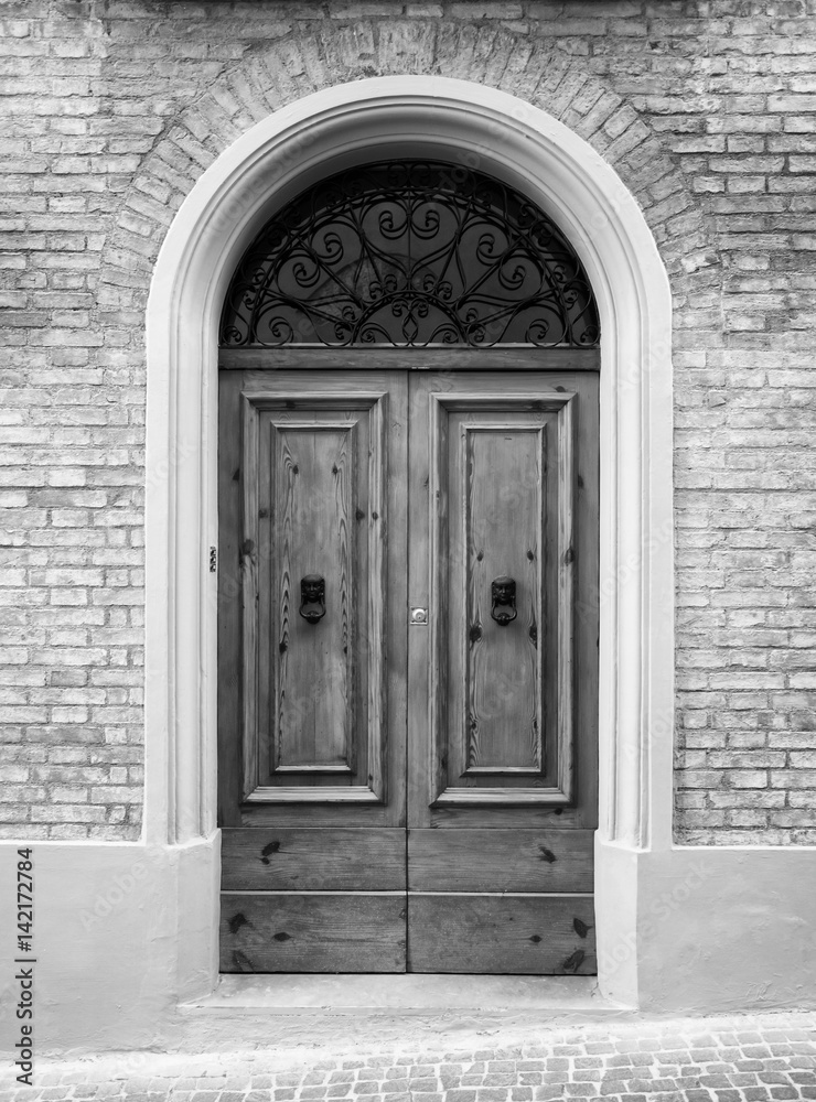 Wooden door in an old Italian house, copy-space, black and white.