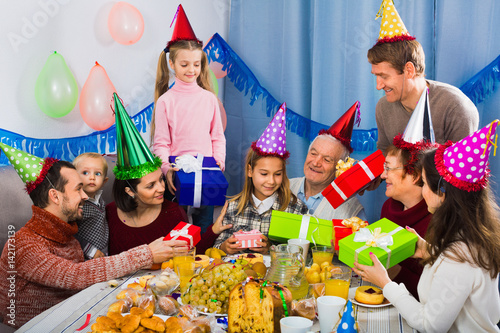 Large family presenting gifts to girl during birthday party