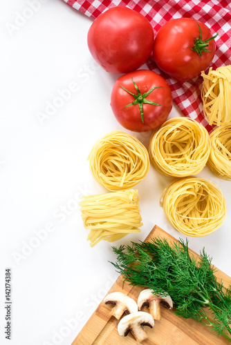 An upper view on an Italian food ingredients isolated in white. Pasta, tomatoes, greens, mushrooms. Top view with copy space.