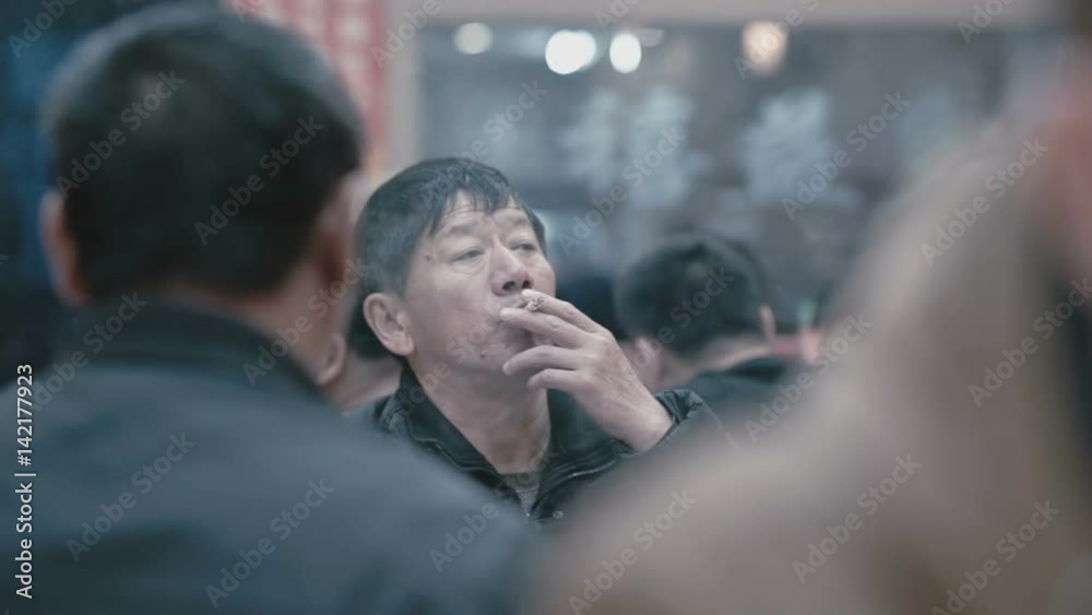 Chinese man sitting in a cafe and smoking a cigarette in slow-motion Chinese man sitting in a cafe and smoking a cigarette in slow-motion
