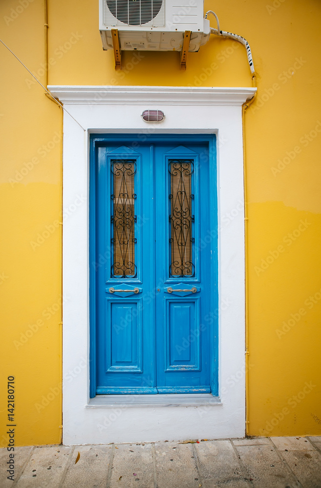 Dark blue old door with glass and forging on a yellow-and-white wall Dark blue old door with glass and forging on a yellow-and-white wall