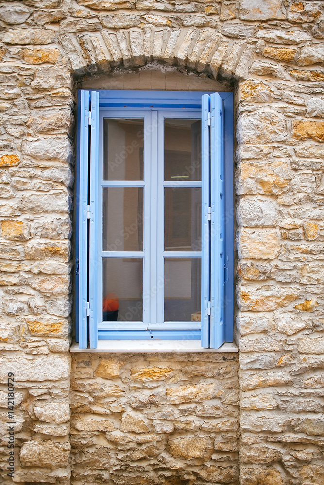 Light blue old window on a stone wall
