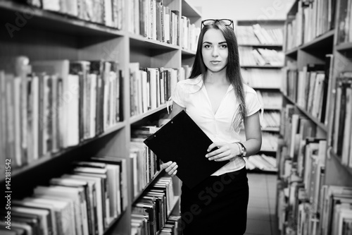 Brunette girl at library with folder of documents, wear on white blouse and black mini skirt. Sexy business woman or teacher concept. Black and white photo.