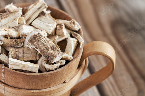 Close-up of marshmallow root (Althaea officinalis) in wooden cup. Copy space