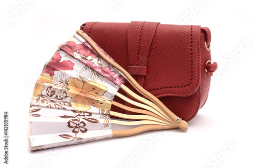 Red leather clutch and hand fan still life