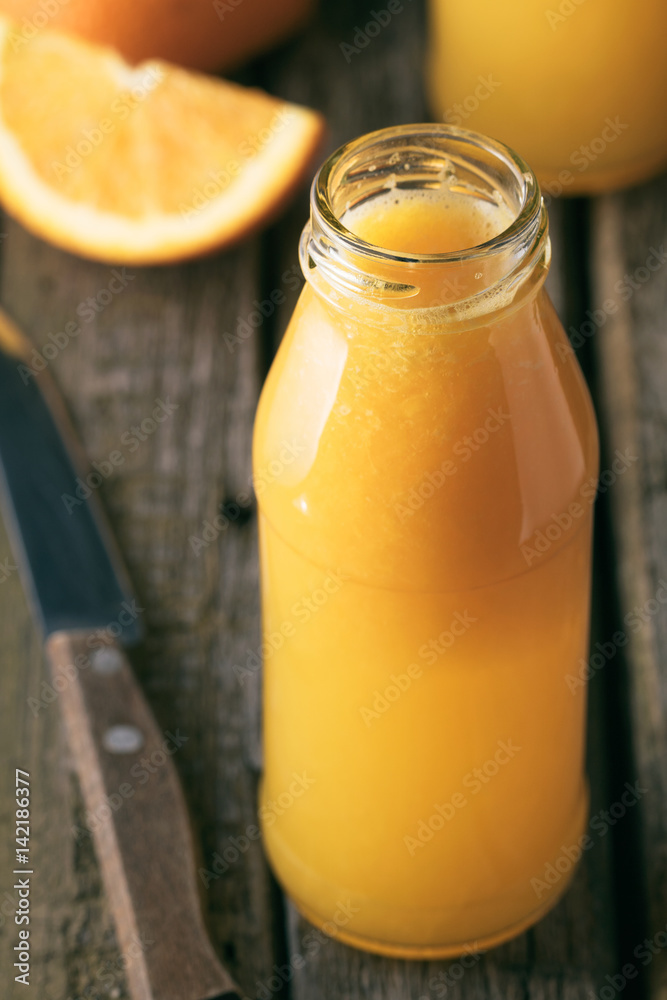Close-up of bottle of fresh orange juice on rustic wooden table Close-up of bottle of fresh orange juice on rustic wooden table