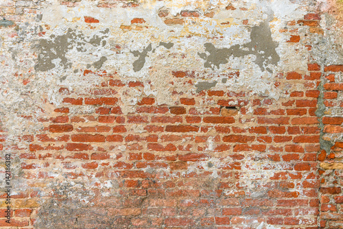 Old brick wall texture  covered with multiply stucco plaster and paint layers  weathered and distressed