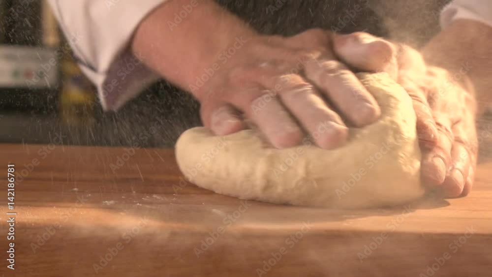 Baker prepares bread. man's hands working the dough on table covered with flour. Slowmotion. Close-up Baker prepares bread. man's hands working the dough on table covered with flour. Slowmotion. Close-up