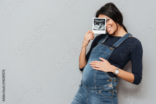 Fotografie Pregnant smiling woman showing ultrasound scans