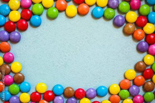 Oval frame of multi-colored candies on blue background