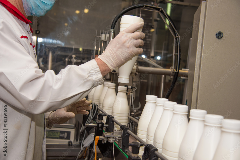 Workers check a bottle of milk on a modern dairy plant