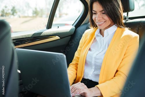 Businesswoman sitting on back seat of car and working © Drobot Dean