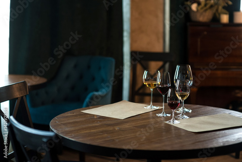 Glasses of red and white wine in a cozy room on wooden table, vintage color with text space