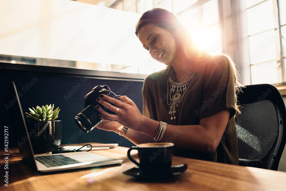 Young female photographer watching her camera while editing her