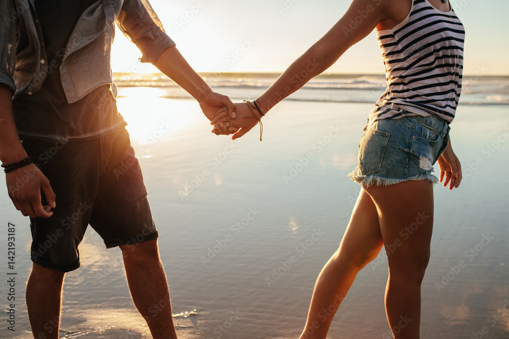 Couple holding hands and walking on the shore Couple holding hands and walking on the shore