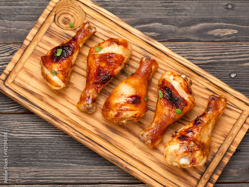 Grilled chicken legs drumsticks on a wooden board