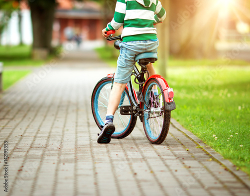 child on a bicycle at asphalt road in summer. Bike in the park