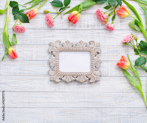 Floral frame with spring flowers and vintage mirror inside over wooden background